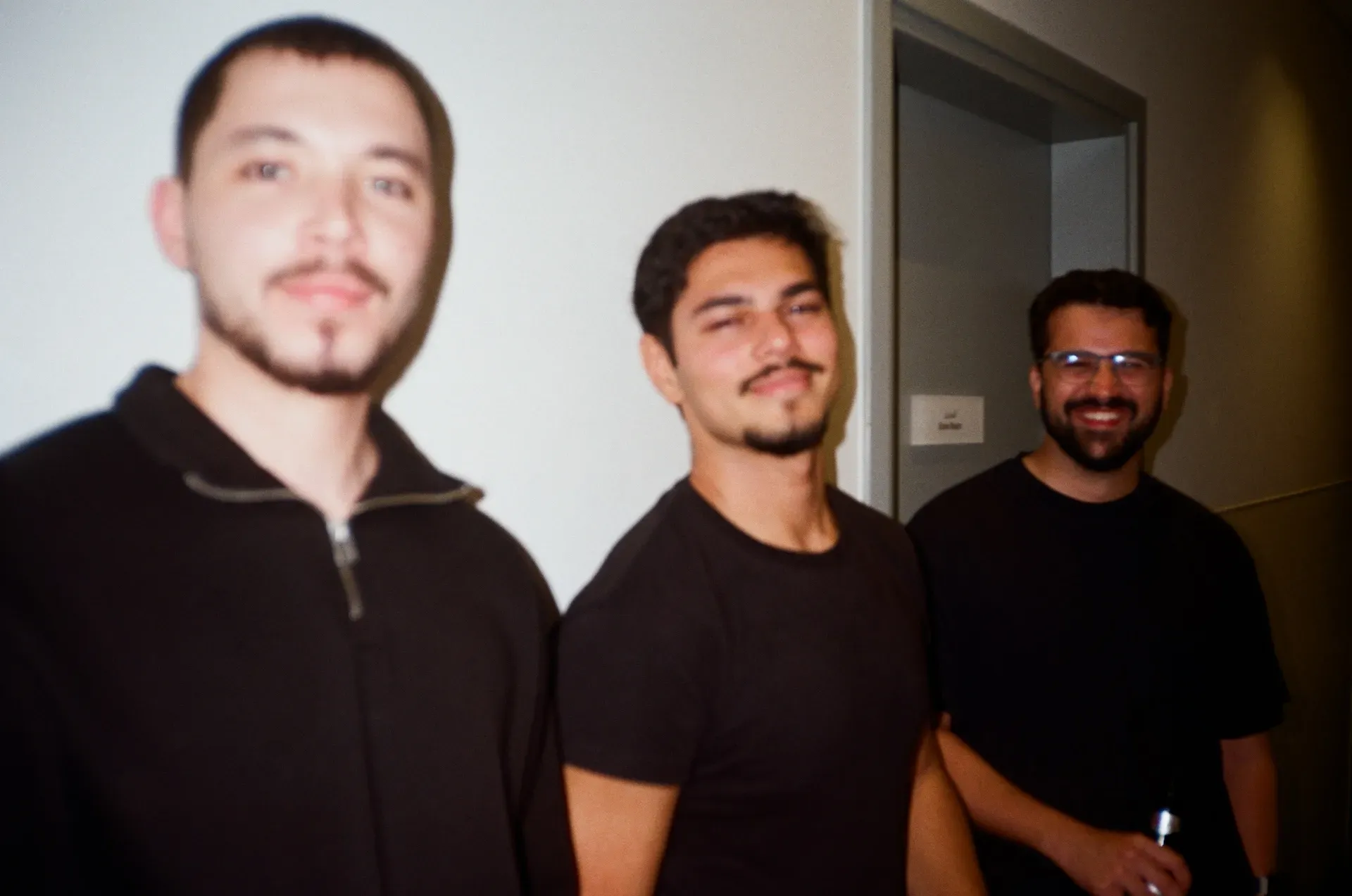 Three men posing together for a portrait indoors