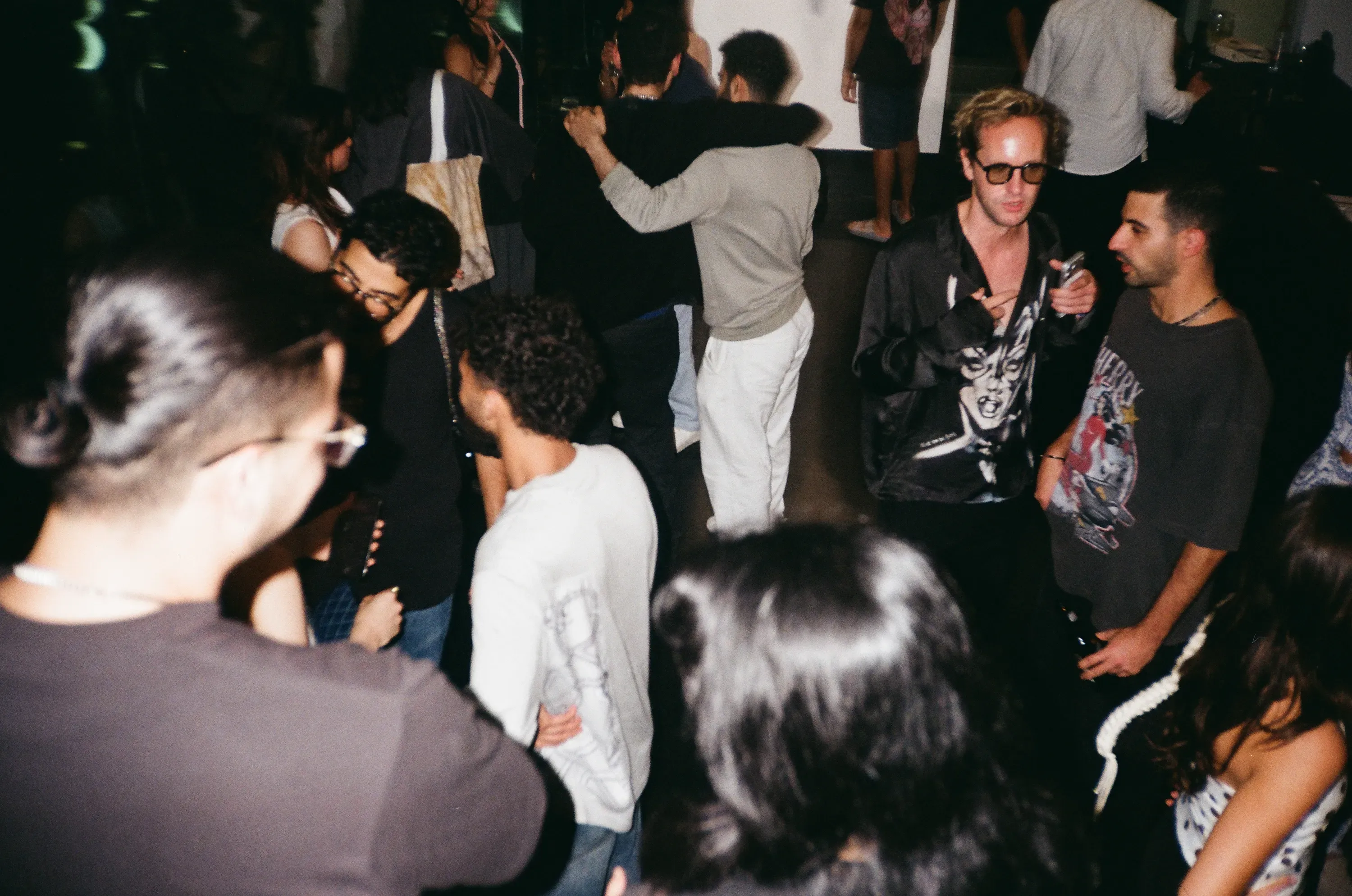 Guests mingling at the Mesh & Mayhem opening, with a large green sculptural figure in the foreground
