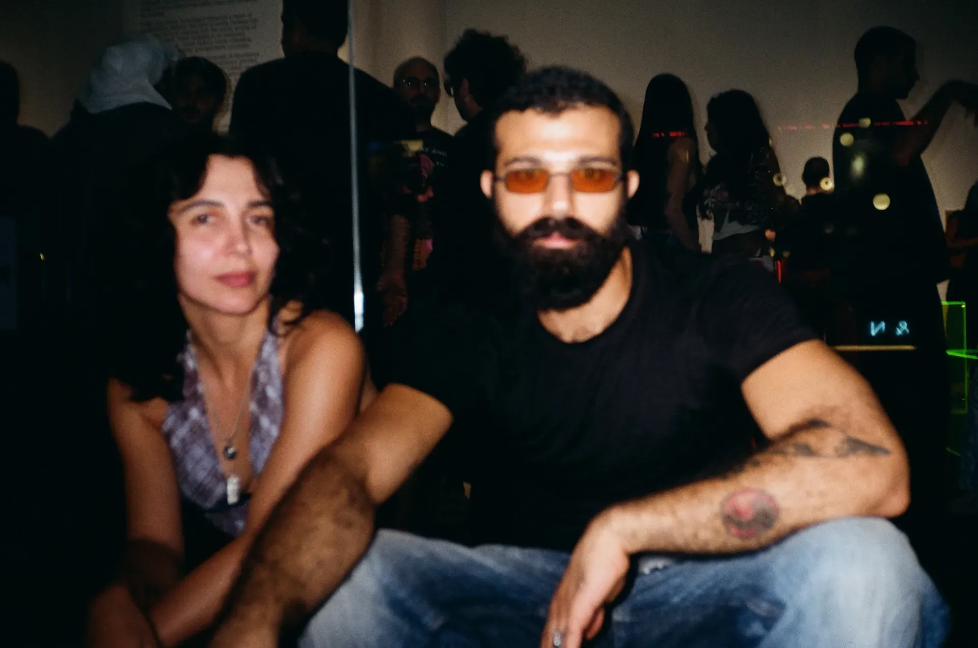 Two seated guests, one wearing tinted glasses, looking at the camera