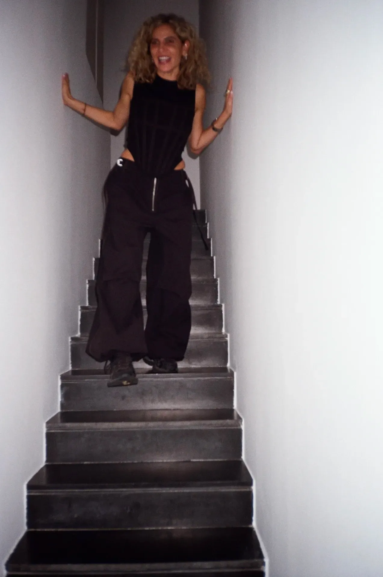 A guest laughing and posing with hands raised on a staircase