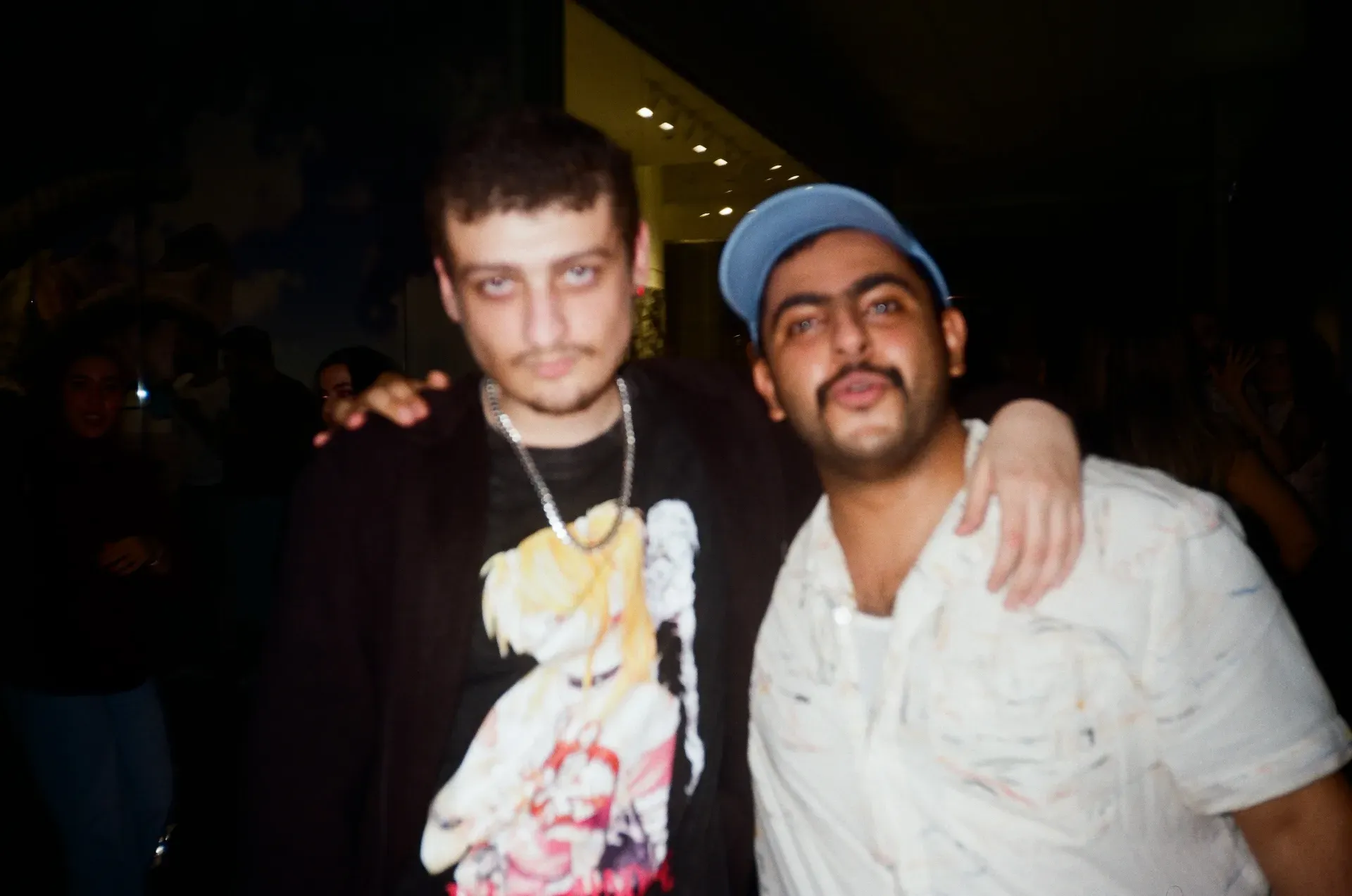 Two guests posing with arms around each other, lit by camera flash